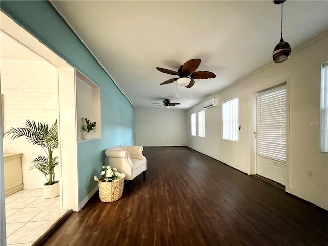 sitting room featuring ceiling fan, an AC wall unit, and wood finished floors