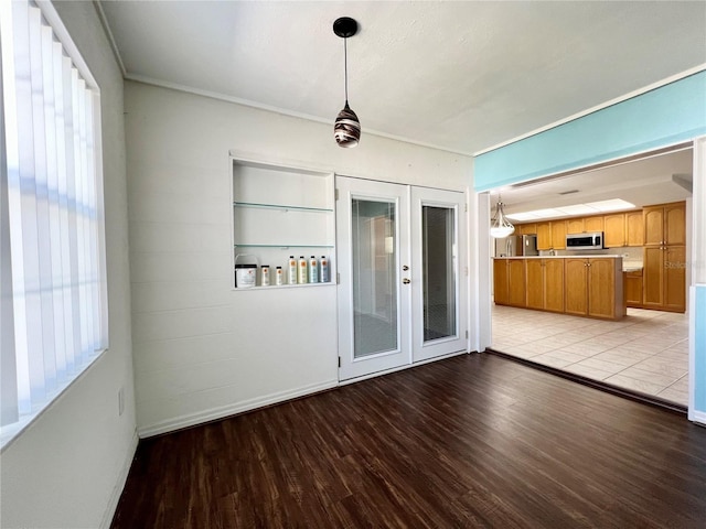 empty room featuring french doors, light wood-style flooring, and crown molding