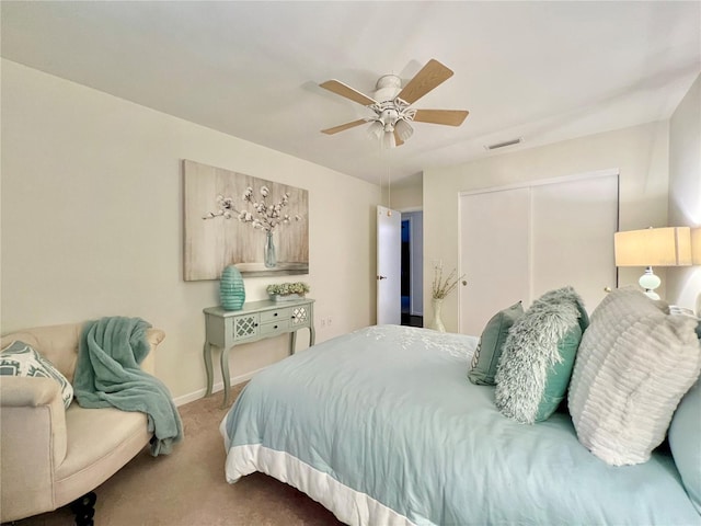 bedroom featuring baseboards, visible vents, a ceiling fan, light colored carpet, and a closet