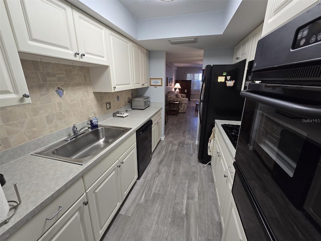 kitchen featuring light hardwood / wood-style floors, white cabinetry, black appliances, and sink