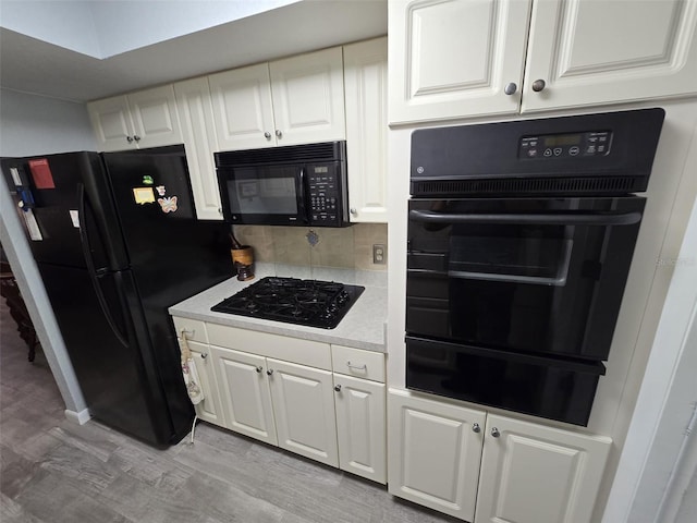 kitchen featuring light hardwood / wood-style flooring, white cabinets, black appliances, and backsplash