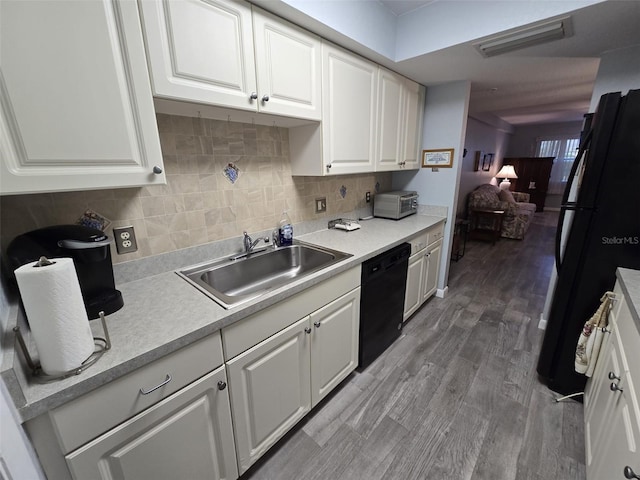 kitchen with black appliances, sink, white cabinets, hardwood / wood-style flooring, and decorative backsplash