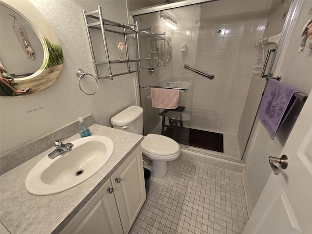 bathroom featuring vanity, toilet, a shower with shower door, and tile patterned flooring