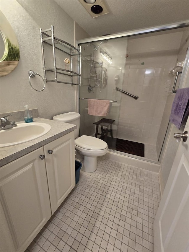 bathroom featuring toilet, vanity, tile patterned floors, and a shower with door