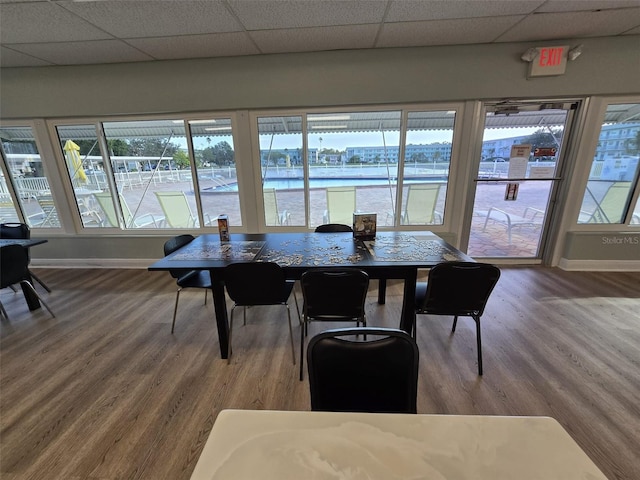 dining space featuring a drop ceiling, hardwood / wood-style floors, and a water view