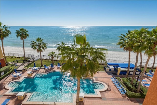 view of pool featuring a patio area, a water view, and a view of the beach