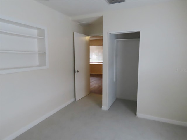 unfurnished bedroom featuring a closet and light colored carpet