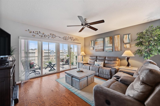 living room featuring ceiling fan, a textured ceiling, and light wood-type flooring