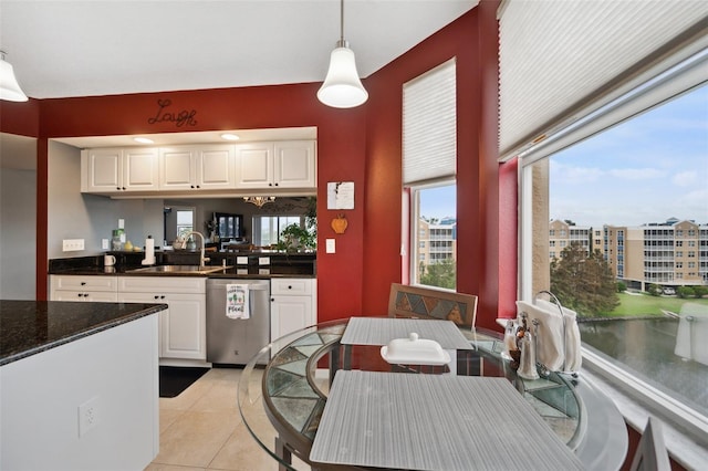 kitchen featuring light tile patterned flooring, white cabinetry, hanging light fixtures, sink, and dishwasher