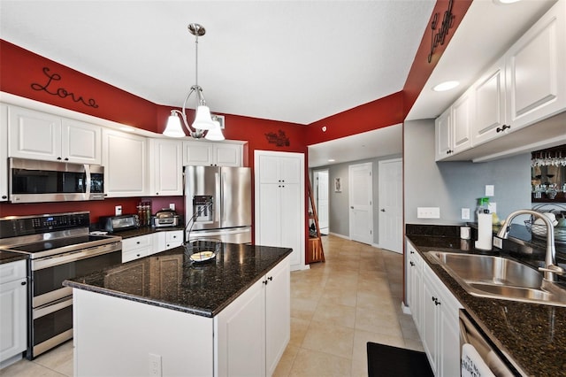 kitchen featuring stainless steel appliances, hanging light fixtures, sink, white cabinets, and a center island