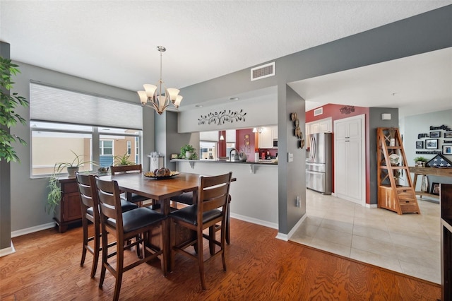 dining room with sink, vaulted ceiling, a notable chandelier, and light hardwood / wood-style flooring