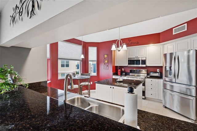 kitchen featuring light tile patterned flooring, appliances with stainless steel finishes, decorative light fixtures, a chandelier, and white cabinets