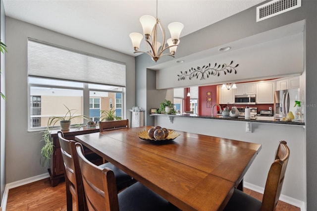 dining area with a wealth of natural light, a notable chandelier, and light hardwood / wood-style floors