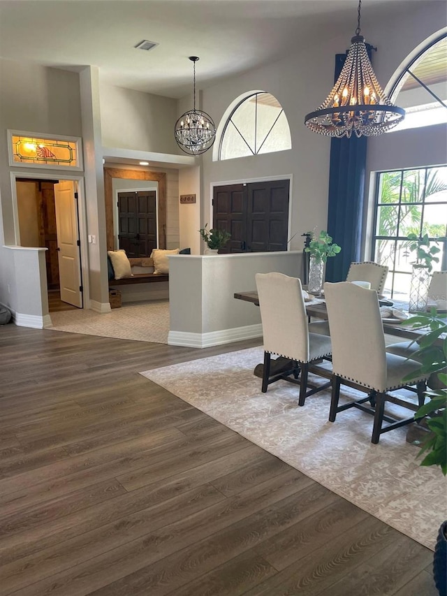 dining space with an inviting chandelier, hardwood / wood-style flooring, and a high ceiling