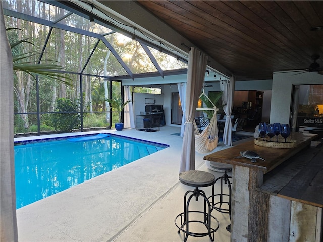 view of pool featuring ceiling fan, a patio area, glass enclosure, and exterior bar