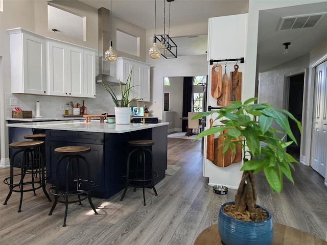 kitchen featuring a breakfast bar area, white cabinetry, light wood-type flooring, pendant lighting, and decorative backsplash