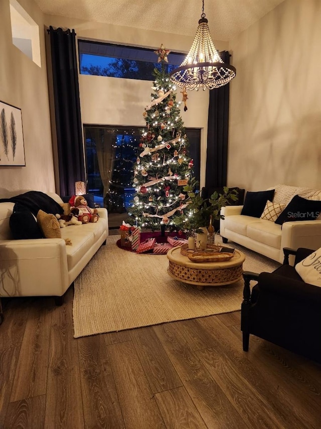 living room featuring dark wood-type flooring, a textured ceiling, and a notable chandelier