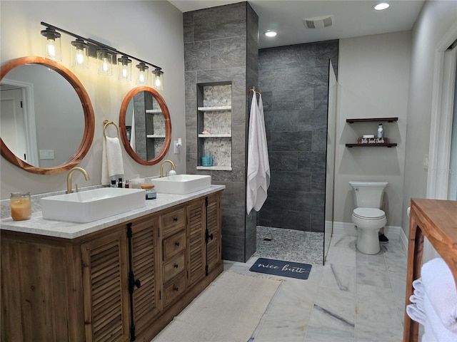 bathroom with vanity, toilet, and a tile shower