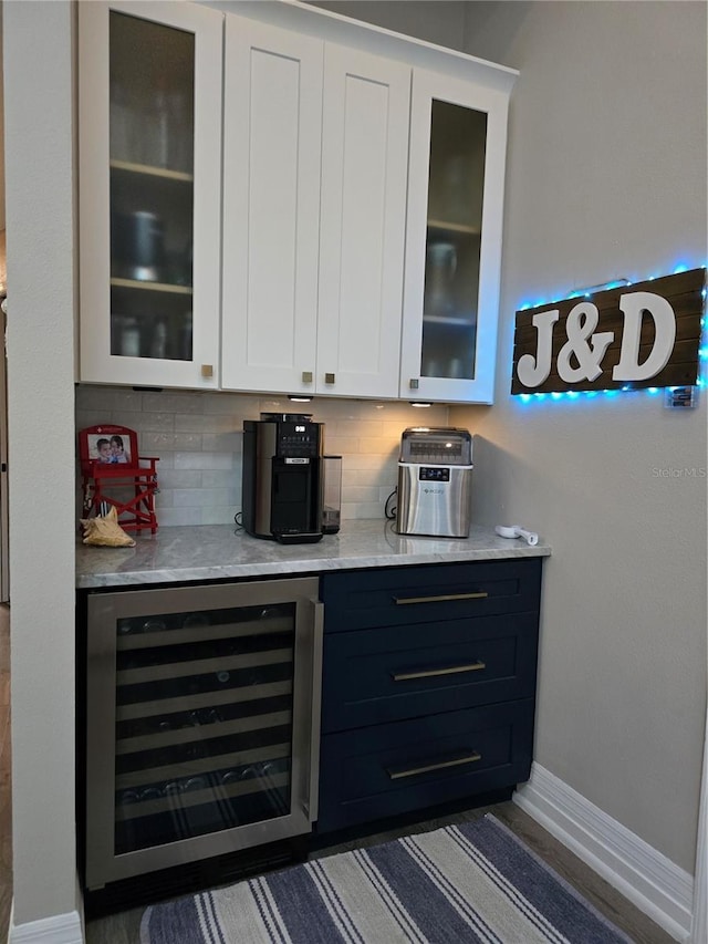 bar featuring decorative backsplash, beverage cooler, and white cabinets