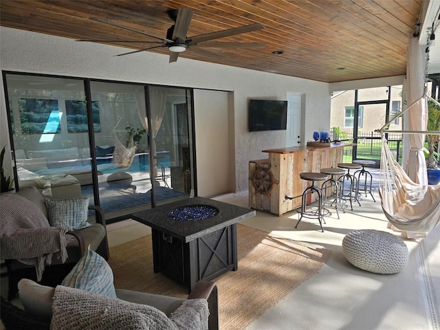 view of patio / terrace featuring exterior bar, ceiling fan, and a fire pit