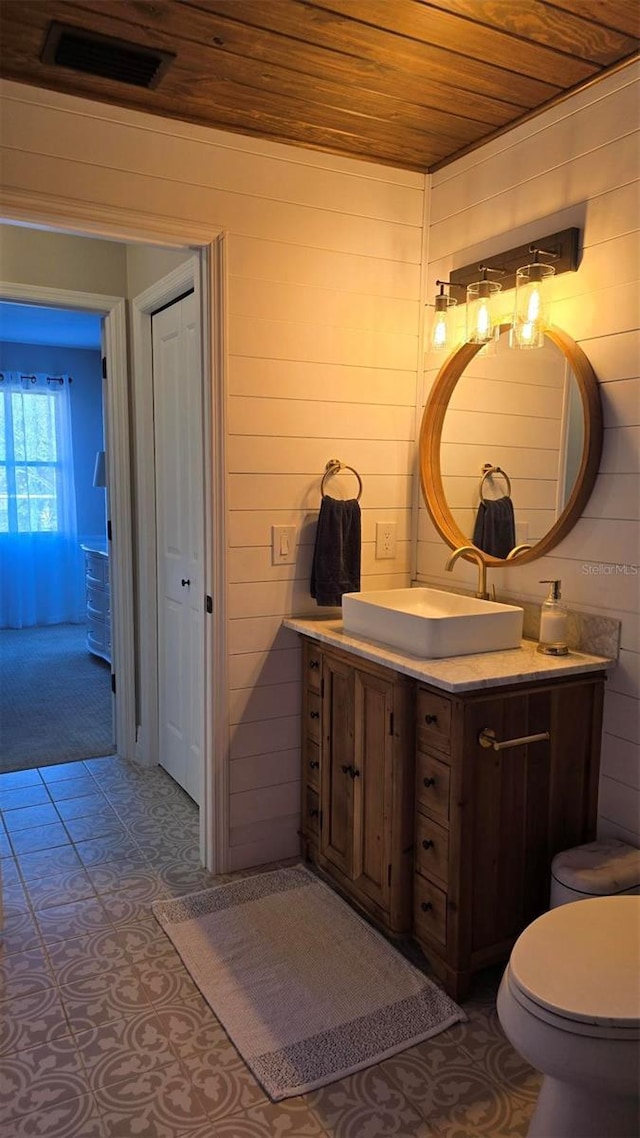 bathroom featuring wood ceiling, vanity, and wood walls