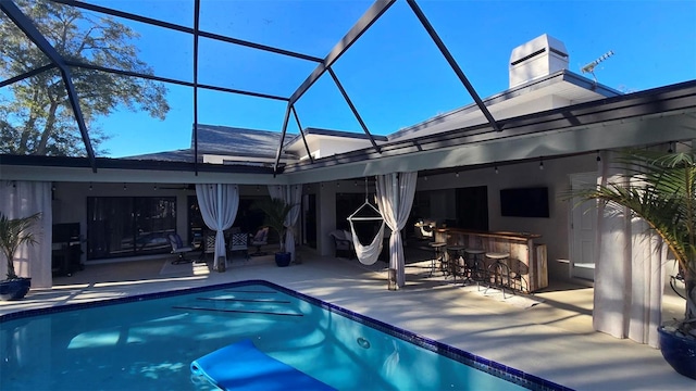 view of swimming pool featuring a lanai, a patio area, and an outdoor bar