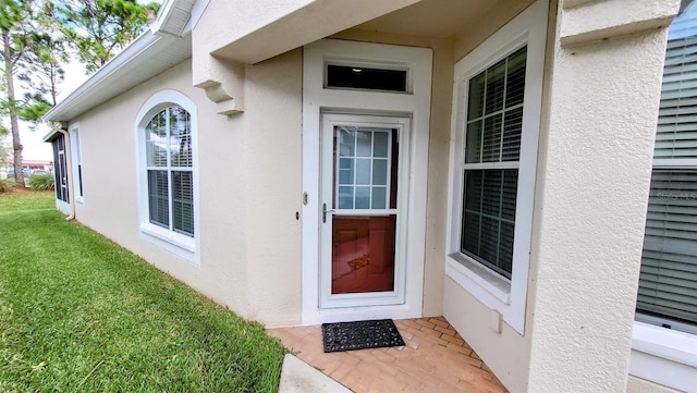 view of exterior entry with a yard