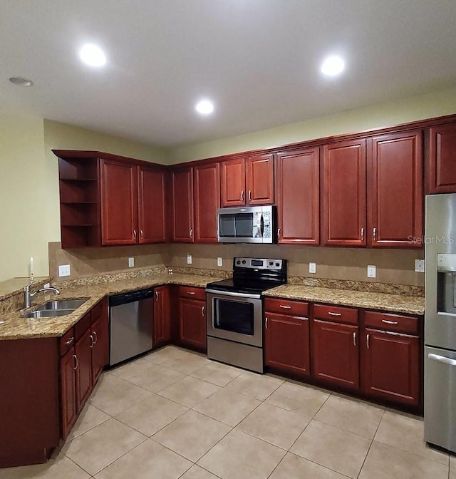 kitchen featuring light stone countertops, sink, light tile patterned flooring, and stainless steel appliances