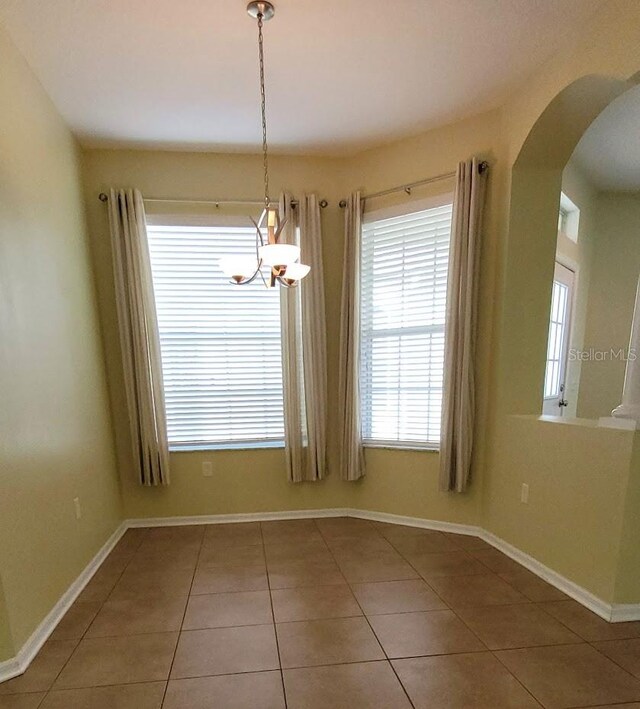 unfurnished dining area featuring tile patterned flooring and a chandelier