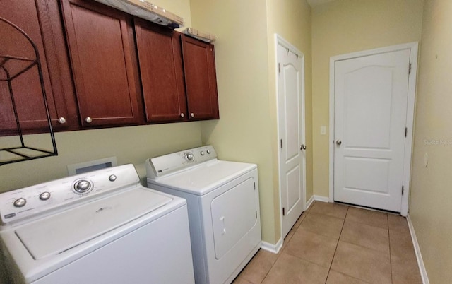 clothes washing area featuring washer and clothes dryer, cabinets, and light tile patterned flooring