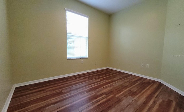 spare room with a wealth of natural light and dark hardwood / wood-style flooring