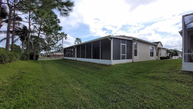 view of home's exterior with a sunroom and a yard