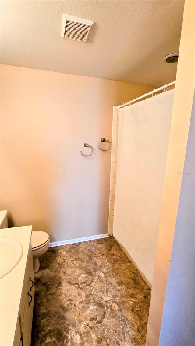 bathroom featuring vanity, a textured ceiling, and toilet