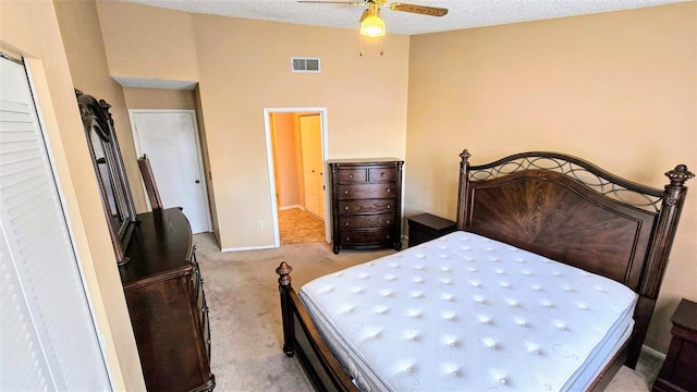 bedroom featuring ceiling fan, light colored carpet, and a textured ceiling