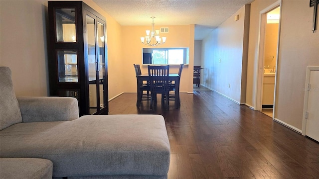 dining room featuring a textured ceiling, a notable chandelier, and dark wood-type flooring