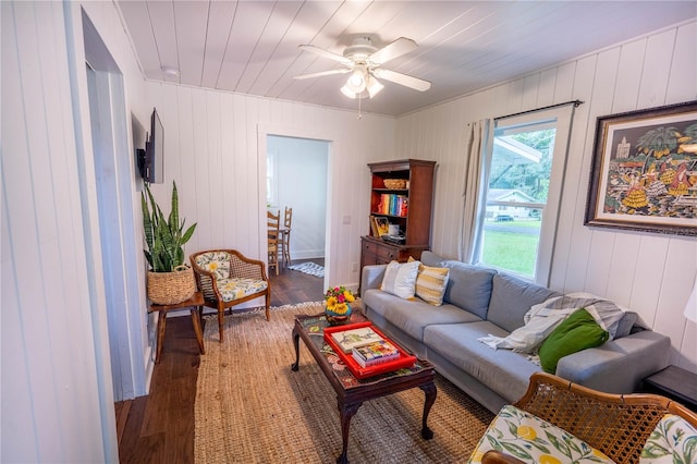 living room featuring dark hardwood / wood-style flooring, ceiling fan, and wood walls