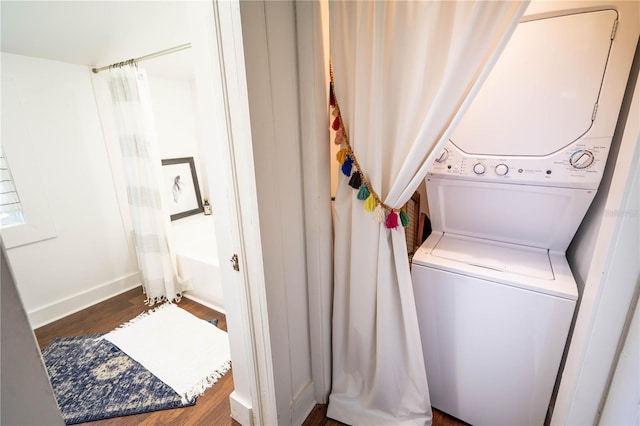 laundry room with hardwood / wood-style floors and stacked washer and dryer