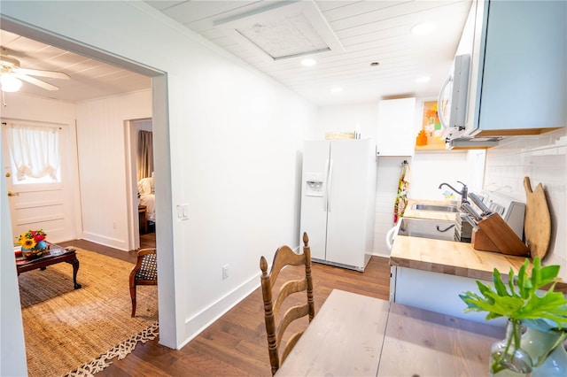 kitchen featuring white appliances, sink, wood-type flooring, white cabinets, and butcher block counters