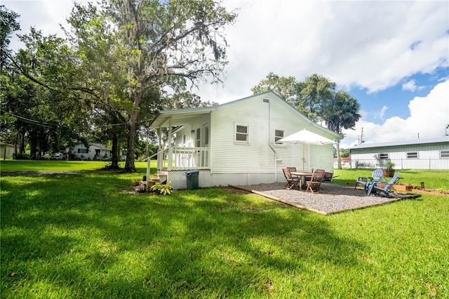 back of property featuring a lawn, a porch, and a patio