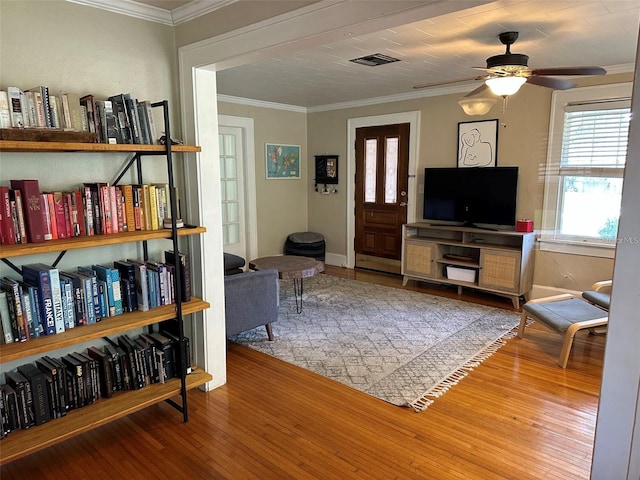 living room with ceiling fan, wood-type flooring, and ornamental molding