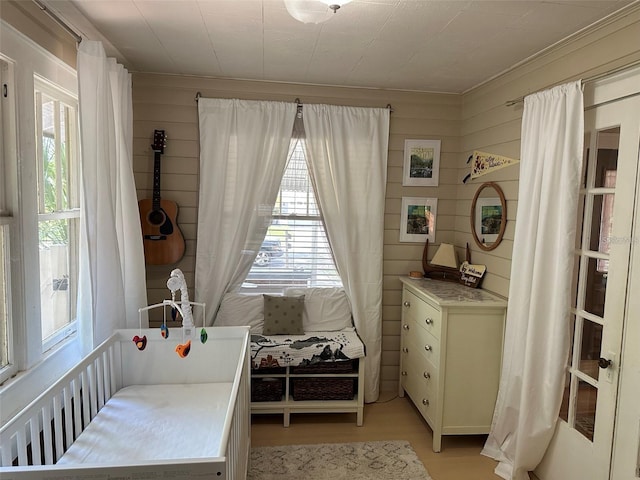 bedroom with wood walls and light hardwood / wood-style flooring