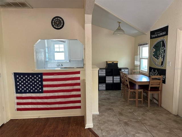 interior space featuring stove, tile patterned floors, and lofted ceiling