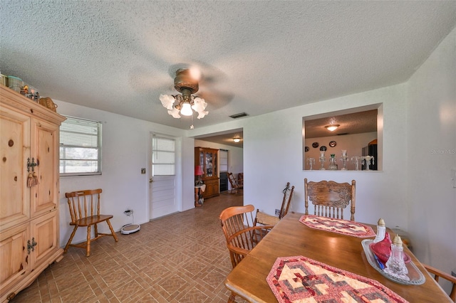 dining area with a textured ceiling and ceiling fan