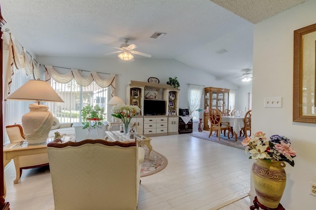 dining room with lofted ceiling, a textured ceiling, light wood-type flooring, and ceiling fan