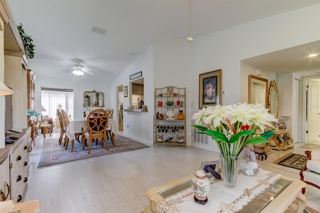 dining area featuring ceiling fan, vaulted ceiling, and light hardwood / wood-style flooring