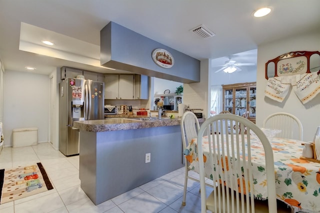 kitchen featuring kitchen peninsula, stainless steel refrigerator with ice dispenser, light tile patterned flooring, and ceiling fan