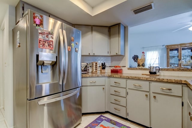 kitchen featuring light tile patterned flooring, stainless steel fridge, white cabinetry, ceiling fan, and decorative backsplash