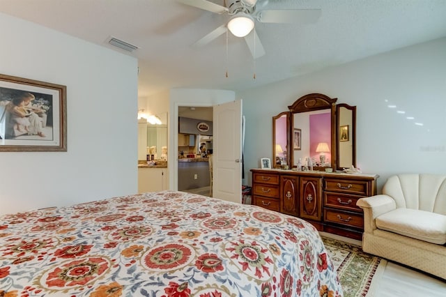 bedroom featuring light hardwood / wood-style floors, a textured ceiling, ensuite bath, and ceiling fan