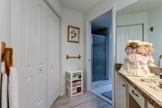 interior space featuring a shower with door, wood-type flooring, and vanity