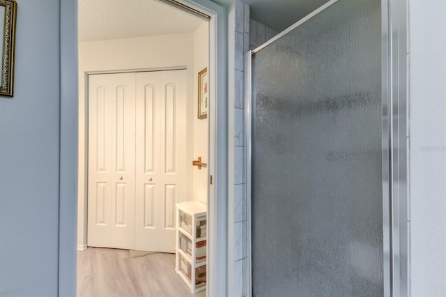 bathroom featuring a shower with door, hardwood / wood-style floors, and a textured ceiling